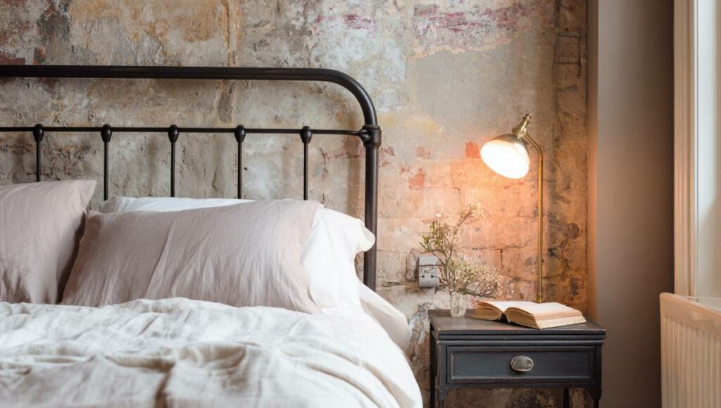 Chambre avec tête de lit en métal et interrupteur installé sur le mur latéral